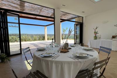 Bouteille de vin rosé entourée de verres vides sur une table en bois, avec une plante en arrière-plan.