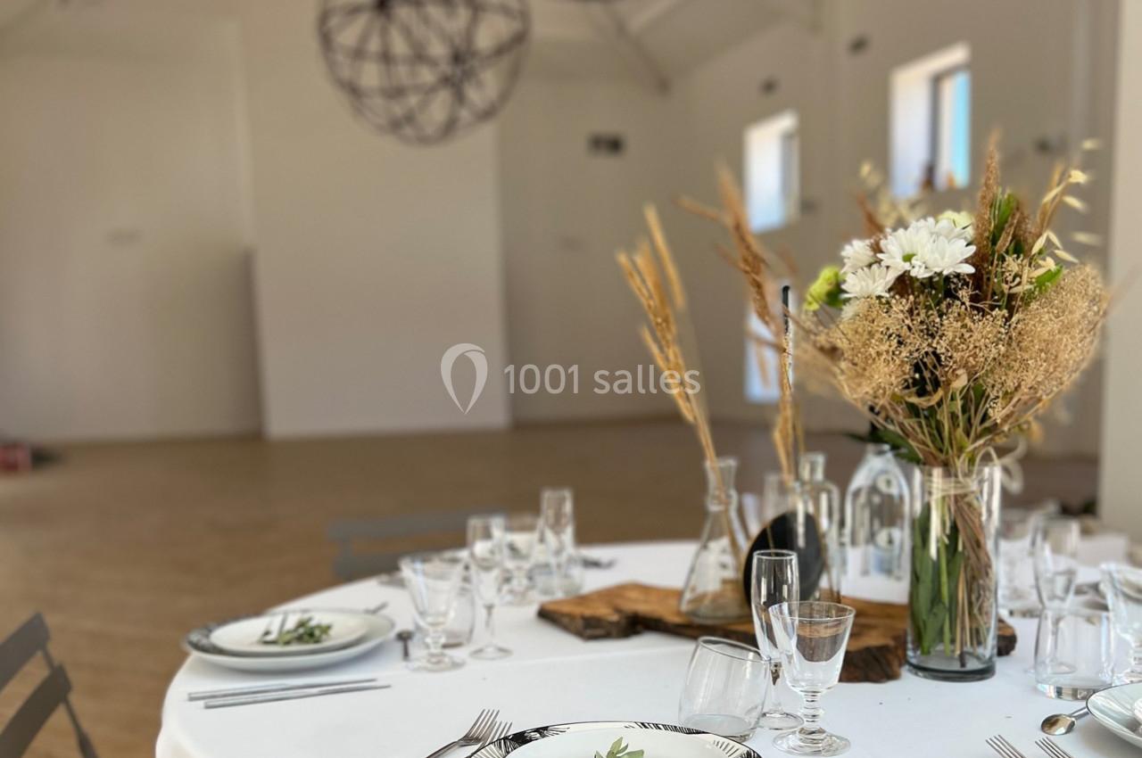 Table dressée avec vaisselle élégante, bouquet de fleurs séchées et décor minimaliste dans une salle lumineuse.