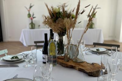 Bouteille de vin rosé entourée de verres vides sur une table en bois, avec une plante en arrière-plan.