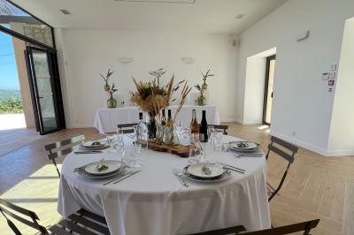 Bouteille de vin rosé entourée de verres vides sur une table en bois, avec une plante en arrière-plan.