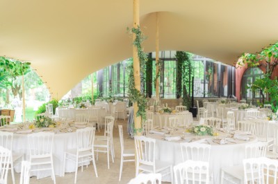 Main d'une personne tenant légèrement une robe blanche, avec un bracelet fin et une bague visible.