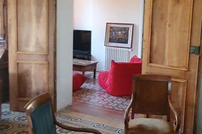 Bâtiment aux murs rouges avec de grandes baies vitrées, entouré d'arbres et d'une fontaine en arrière-plan.