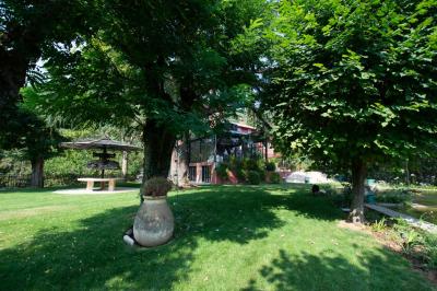 Bâtiment aux murs rouges avec de grandes baies vitrées, entouré d'arbres et d'une fontaine en arrière-plan.