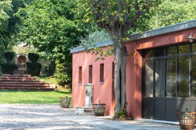 Bâtiment aux murs rouges avec de grandes baies vitrées, entouré d'arbres et d'une fontaine en arrière-plan.