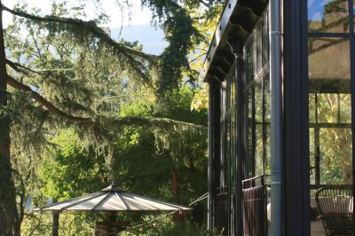 Bâtiment aux murs rouges avec de grandes baies vitrées, entouré d'arbres et d'une fontaine en arrière-plan.