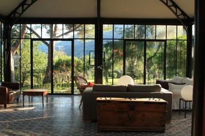 Bâtiment aux murs rouges avec de grandes baies vitrées, entouré d'arbres et d'une fontaine en arrière-plan.