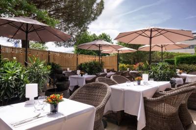 Salle de soins avec table de massage, serviette, produits de beauté, bougies allumées et plantes décoratives.