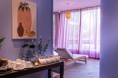 Salle de soins avec table de massage, serviette, produits de beauté, bougies allumées et plantes décoratives.