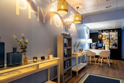 Salle de soins avec table de massage, serviette, produits de beauté, bougies allumées et plantes décoratives.