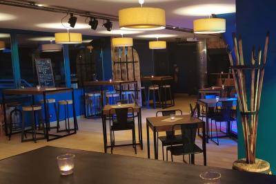 Salle moderne avec tables hautes en bois, chaises en métal, éclairage chaleureux et grandes fenêtres avec stores.