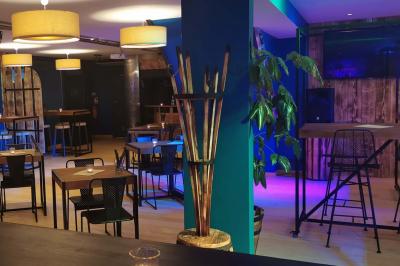 Salle moderne avec tables hautes en bois, chaises en métal, éclairage chaleureux et grandes fenêtres avec stores.