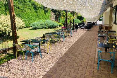 Salle moderne avec tables hautes en bois, chaises en métal, éclairage chaleureux et grandes fenêtres avec stores.