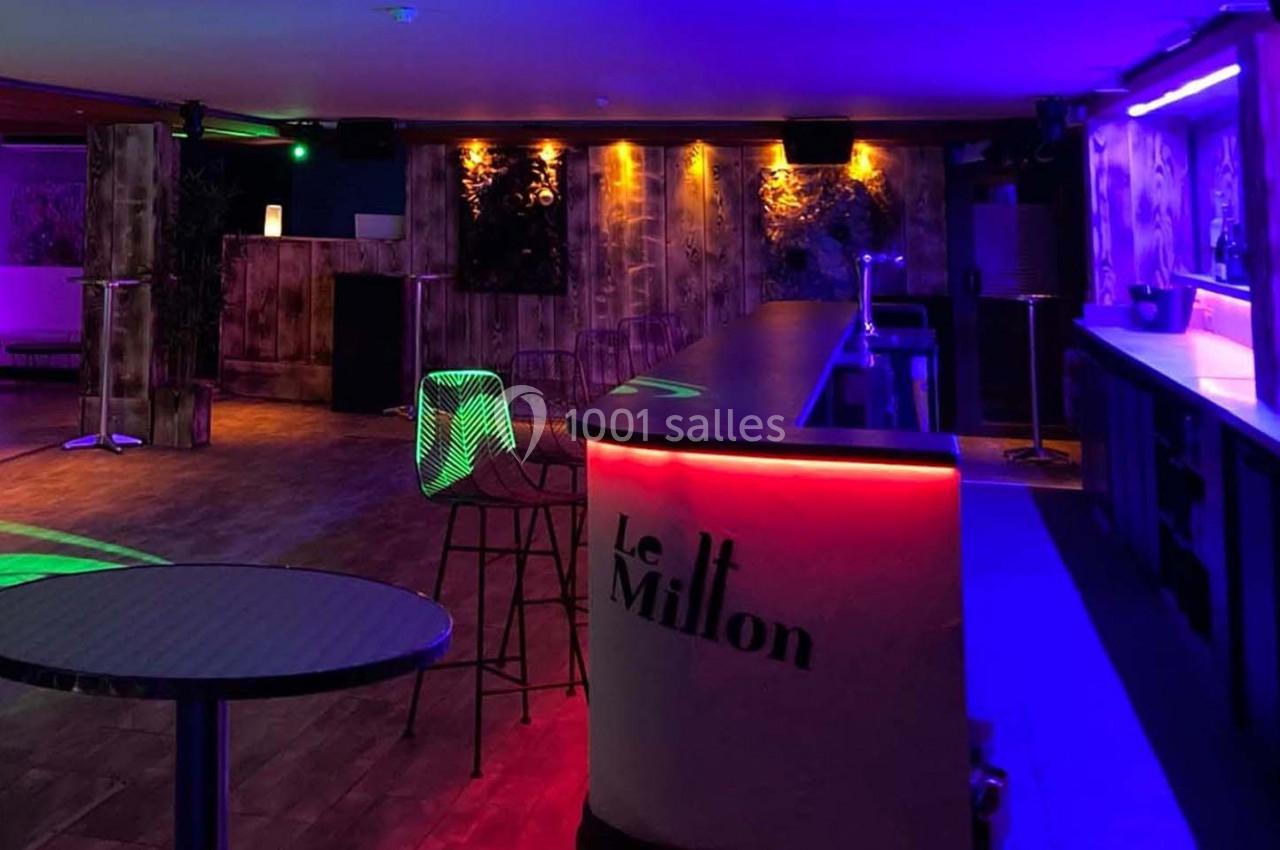 Salle de bar avec éclairage coloré, comptoir lumineux et chaises hautes dans une ambiance tamisée.