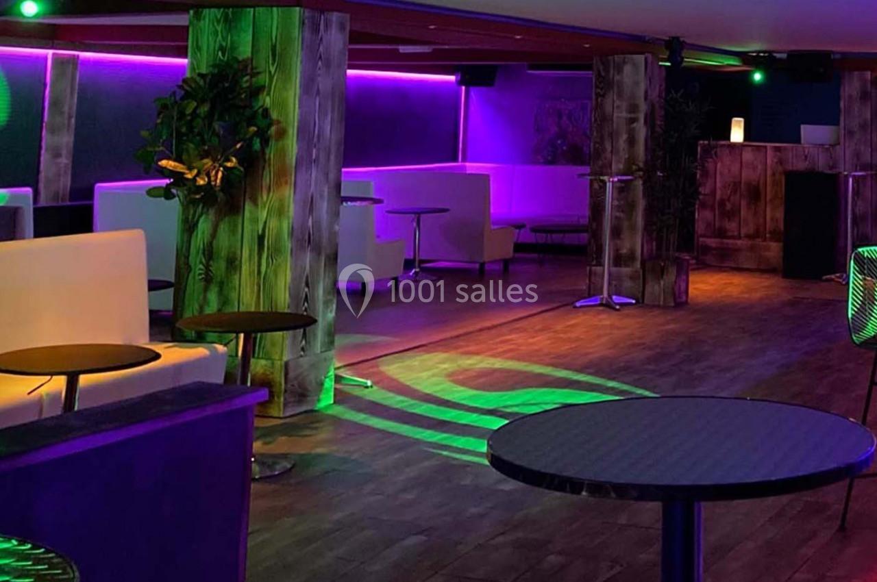 Salle de réception avec éclairage coloré, mobilier moderne et ambiance tamisée.