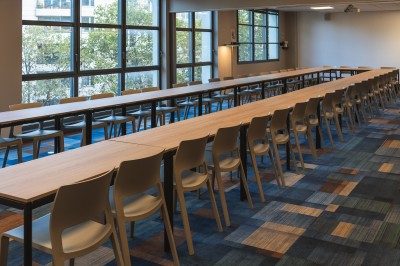 Salle de conférence moderne avec des rangées de sièges orange et un projecteur suspendu au plafond.