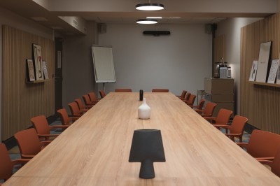 Salle de conférence moderne avec des rangées de sièges orange et un projecteur suspendu au plafond.