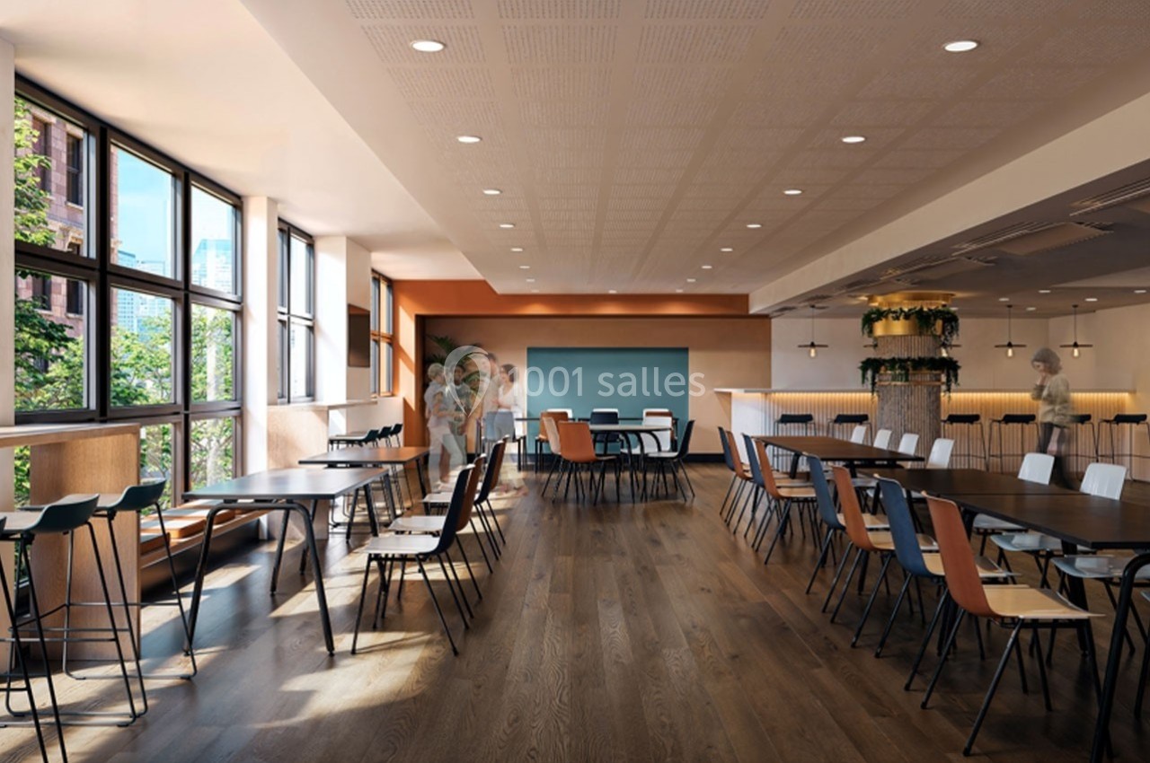 Salle lumineuse avec de grandes fenêtres, tables en bois, chaises colorées et décoration végétale.