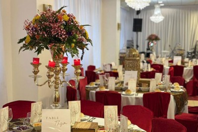 Des roses rouges dans une cage décorative dorée, entourées de tables ornées pour un événement festif.