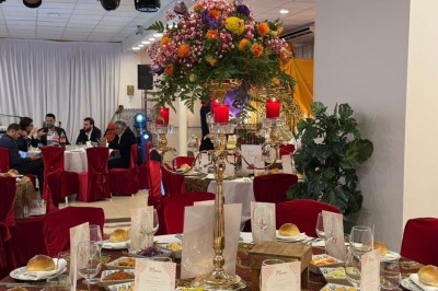 Des roses rouges dans une cage décorative dorée, entourées de tables ornées pour un événement festif.