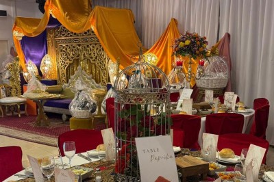 Des roses rouges dans une cage décorative dorée, entourées de tables ornées pour un événement festif.