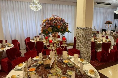 Des roses rouges dans une cage décorative dorée, entourées de tables ornées pour un événement festif.