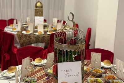 Des roses rouges dans une cage décorative dorée, entourées de tables ornées pour un événement festif.