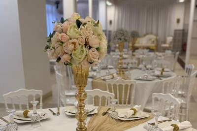 Des roses rouges dans une cage décorative dorée, entourées de tables ornées pour un événement festif.