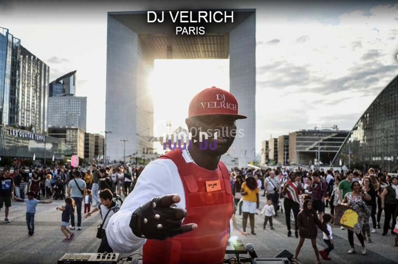 Un DJ mixant en plein air devant une foule, avec l'Arche de la Défense en arrière-plan.