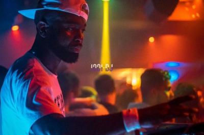 Un DJ mixe en plein air devant une foule, avec l'Arche de la Défense en arrière-plan.