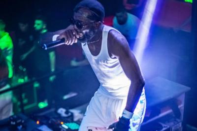 Un DJ mixe en plein air devant une foule, avec l'Arche de la Défense en arrière-plan.