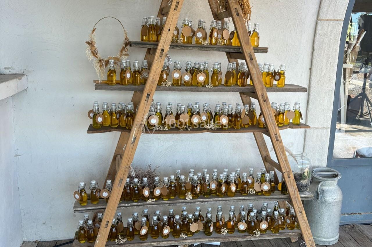 Étagère en bois en forme de triangle exposant des bouteilles d'huile disposées en rangées sur plusieurs niveaux.