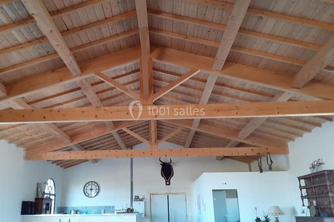 Plafond en bois avec poutres apparentes dans une pièce lumineuse, décorée d'objets muraux et d'une tête de taureau.