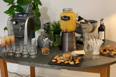 Table avec machine à café, carafe de punch, verres, snacks salés et bouteilles de vin dans un cadre convivial.