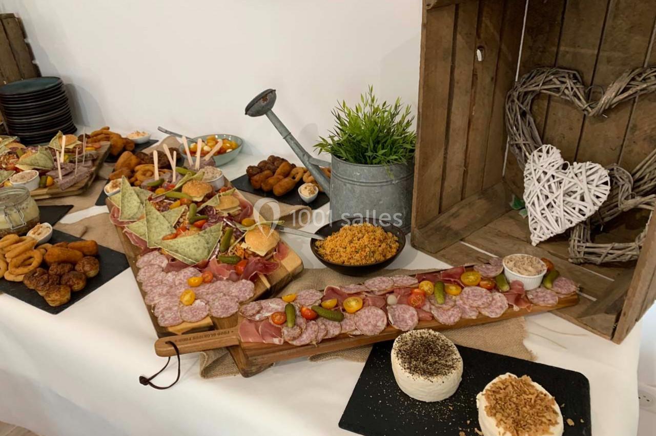 Plateau de charcuterie, fromages et amuse-bouches disposés sur une table avec décoration rustique en bois.