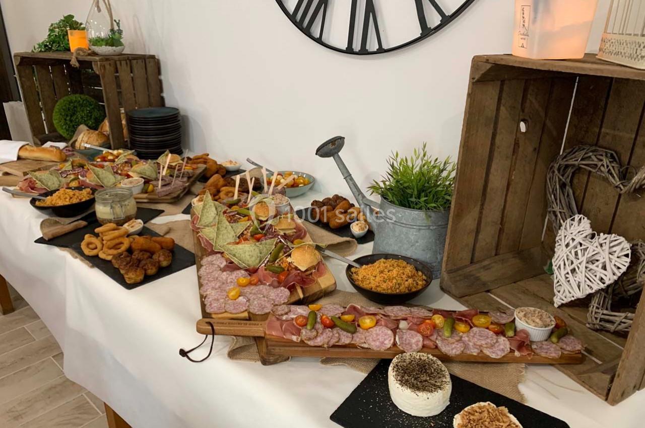 Buffet varié avec charcuterie, fromages, verrines, pains et décor rustique sur une table blanche.