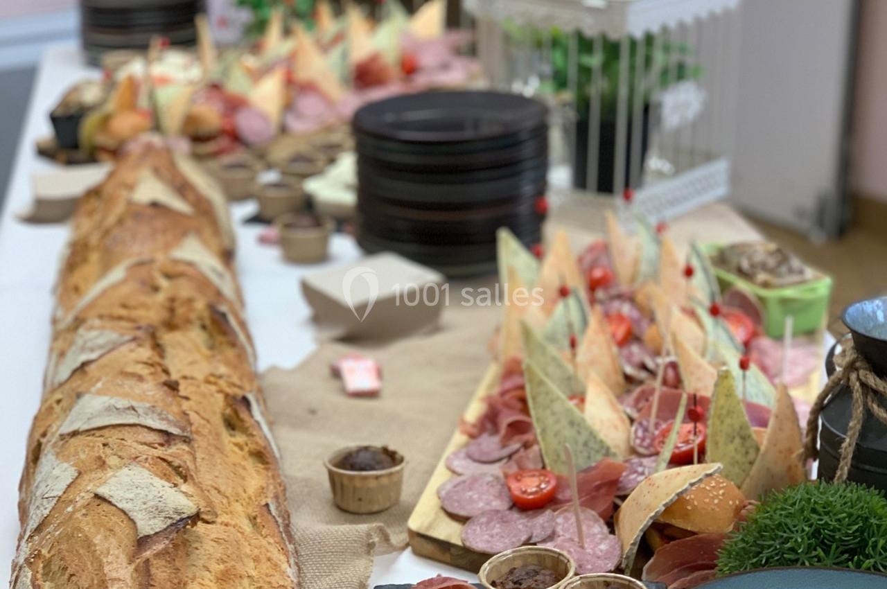 Buffet avec baguette, charcuteries, fromages et verrines, disposés sur une table décorée de plantes et accessoires rustiques.