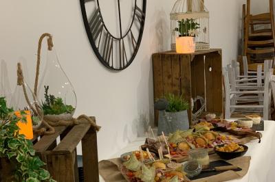 Table avec machine à café, carafe de punch, verres, snacks salés et bouteilles de vin dans un cadre convivial.