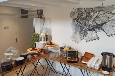 Table avec machine à café, carafe de punch, verres, snacks salés et bouteilles de vin dans un cadre convivial.