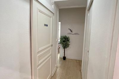 Salle de classe lumineuse avec des tables et chaises noires alignées, un projecteur suspendu et une grande fenêtre.