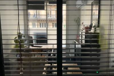 Salle de classe lumineuse avec des tables et chaises noires alignées, un projecteur suspendu et une grande fenêtre.