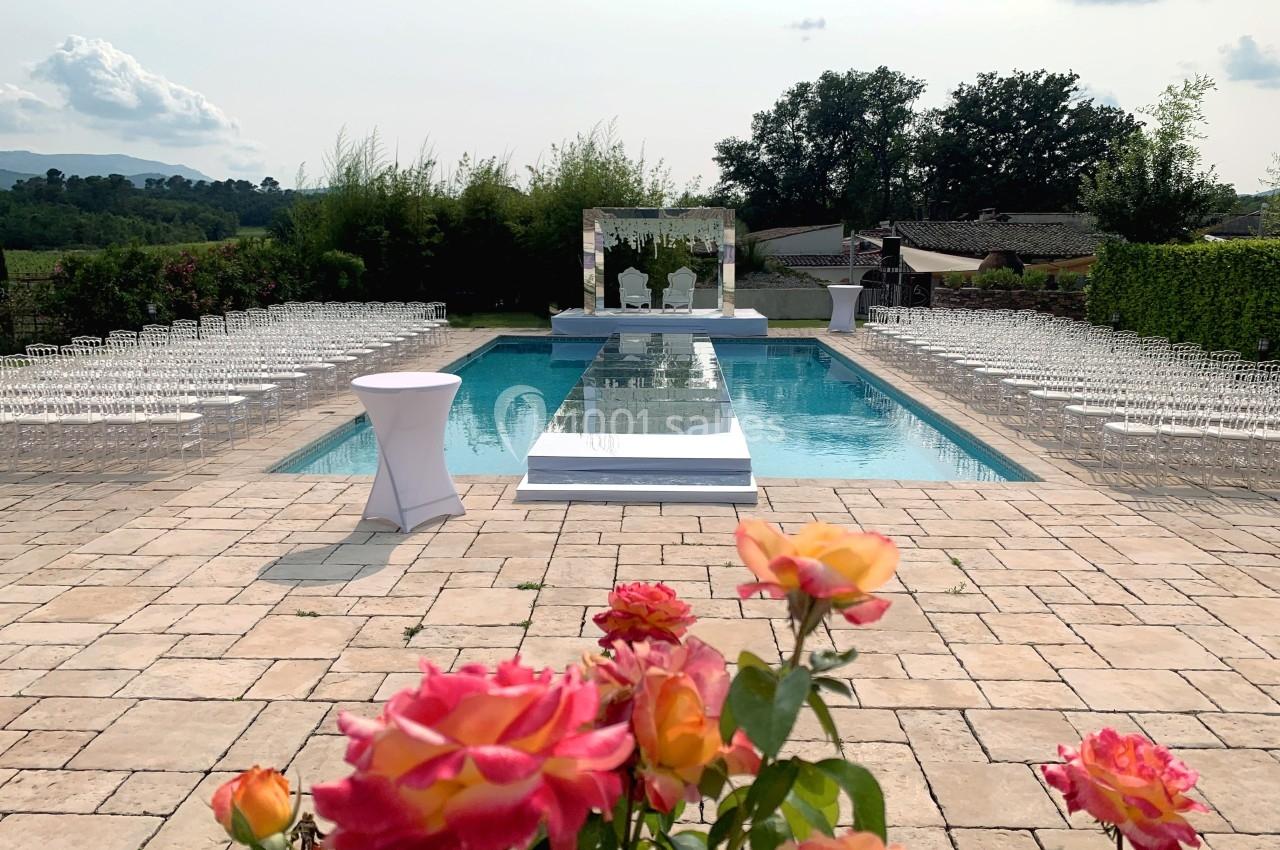 Aménagement d'une cérémonie en plein air avec une piscine centrale, des chaises alignées et des roses au premier plan.