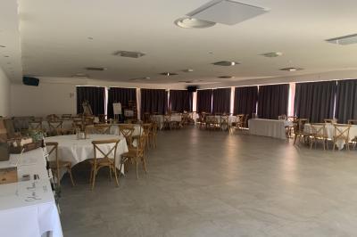 Allée centrale bordée de chaises blanches menant à une arche décorée de fleurs, dans un cadre extérieur arboré.