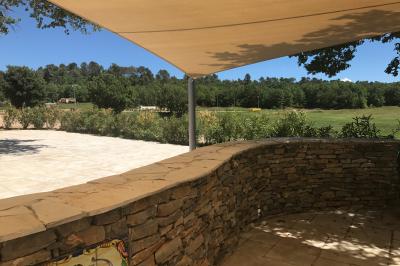 Allée centrale bordée de chaises blanches menant à une arche décorée de fleurs, dans un cadre extérieur arboré.