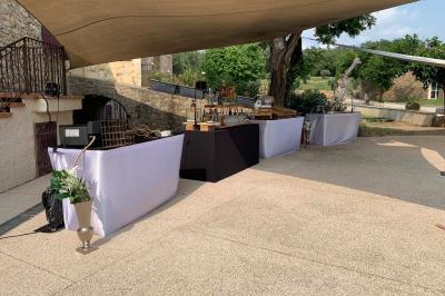Allée centrale bordée de chaises blanches menant à une arche décorée de fleurs, dans un cadre extérieur arboré.