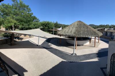 Allée centrale bordée de chaises blanches menant à une arche décorée de fleurs, dans un cadre extérieur arboré.