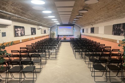 Intérieur d'une structure voûtée en pierre, éclairée par des lumières colorées roses, bleues et vertes.