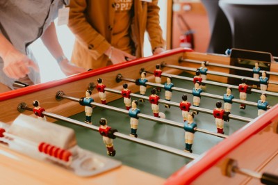 Serveur portant un plateau dans un événement en plein air sous des tentes, avec des invités assis et debout.