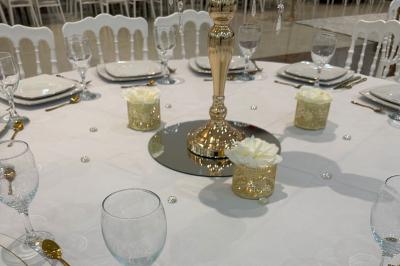 Salle lumineuse avec miroir doré, tabouret, banc noir, portant à vêtements et tableau décoratif sur un mur blanc.
