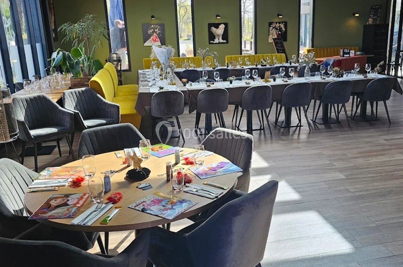 Salle de réception lumineuse avec tables décorées, chaises modernes et grandes baies vitrées donnant sur un espace extérieur.