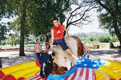 Kiosque en toit de chaume entouré d'arbres, situé dans une cour pavée avec des voiles d'ombrage.
